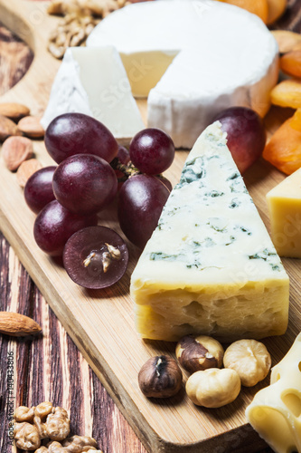 Assorted fresh cheese, fruits and nuts on a wooden table