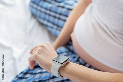 Pregnant woman checking time on watch