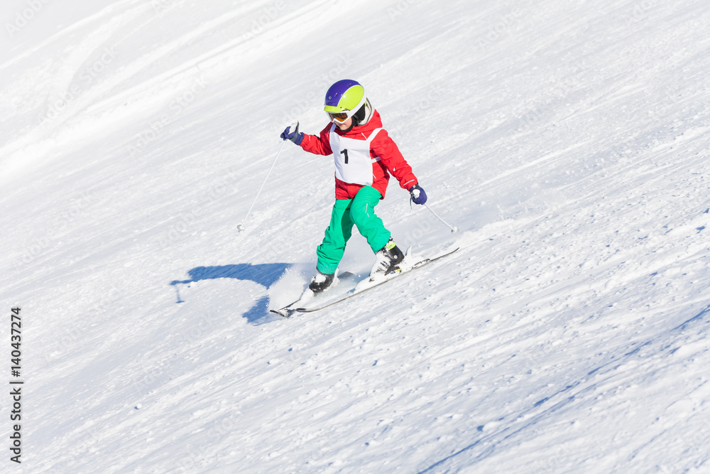 Little skier racing in snowy mountain slope