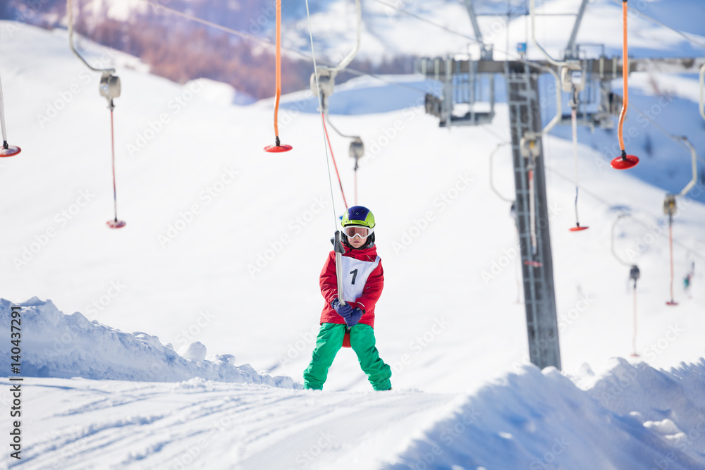 Little skier using a button lift on the slope