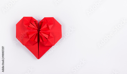 Red origami heart on a white background. A valentine made of paper. Copy space