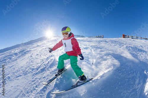 Active kid boy skiing in mountains at sunny day
