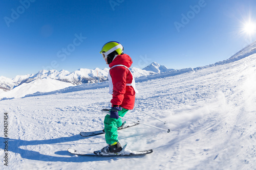 Skiing boy hitting down a hill in alpine resort