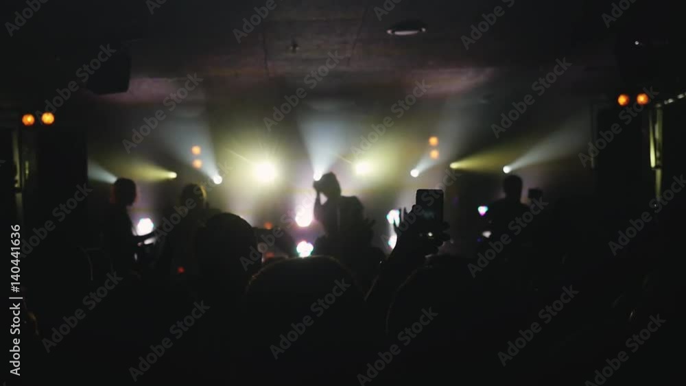 Fans waving their hands and hold the phone with digital displays in slowmotion. People crowd partying at rock concert in a night club. 1920x1080 Fans waving their hands and hold the phone with digital displays in slowmotion. People crowd partying at rock concert in a night club. 1920x1080