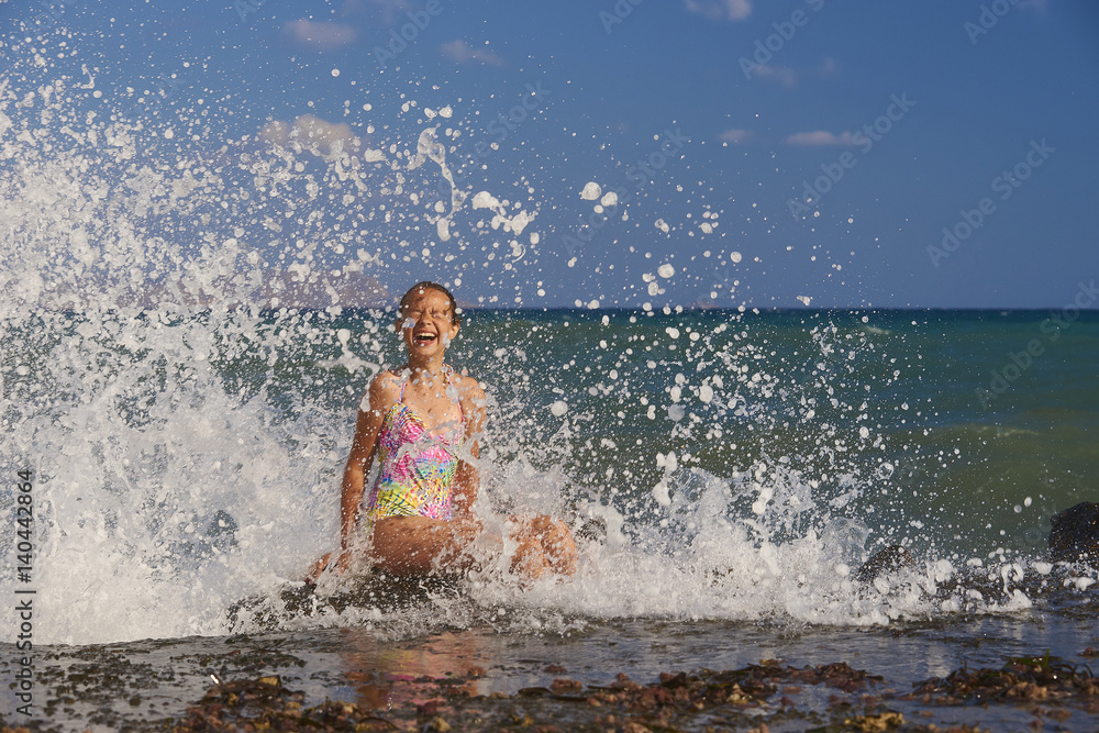 A young girl is enjoying the splashing droplets.