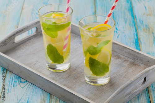 lemonade with mint on rocks served in a glass with a straw