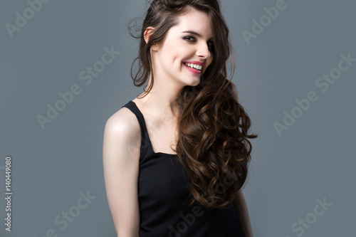 Smiling Woman with long hair on a gray background.