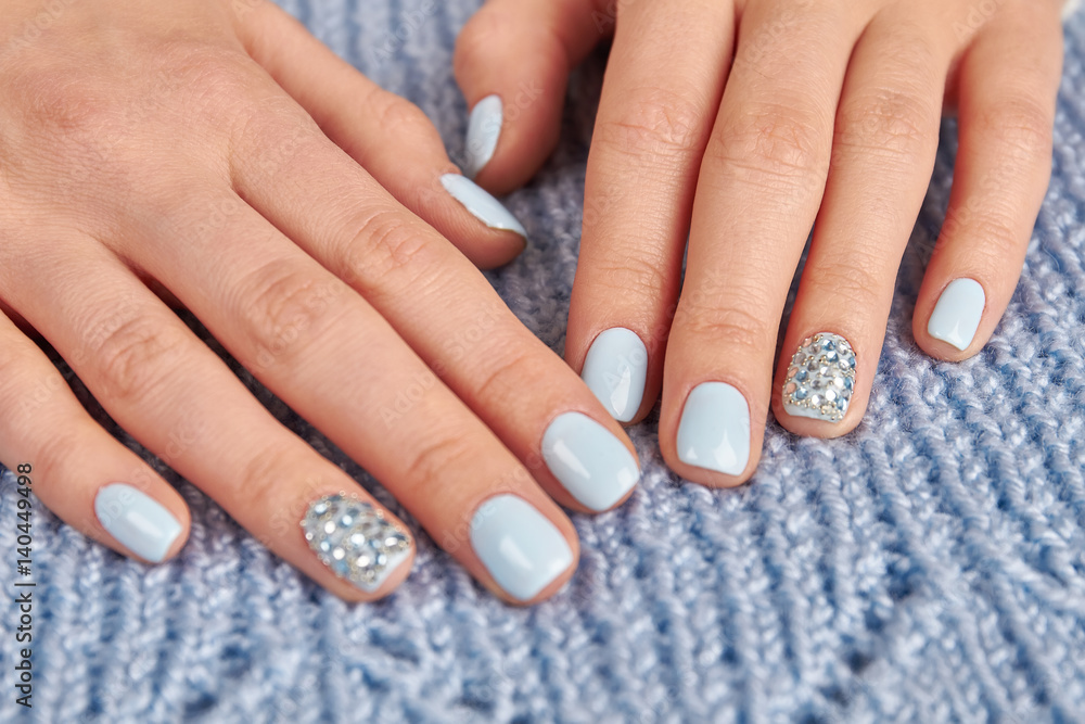 Beautifully designed manicure on a blue knit background.