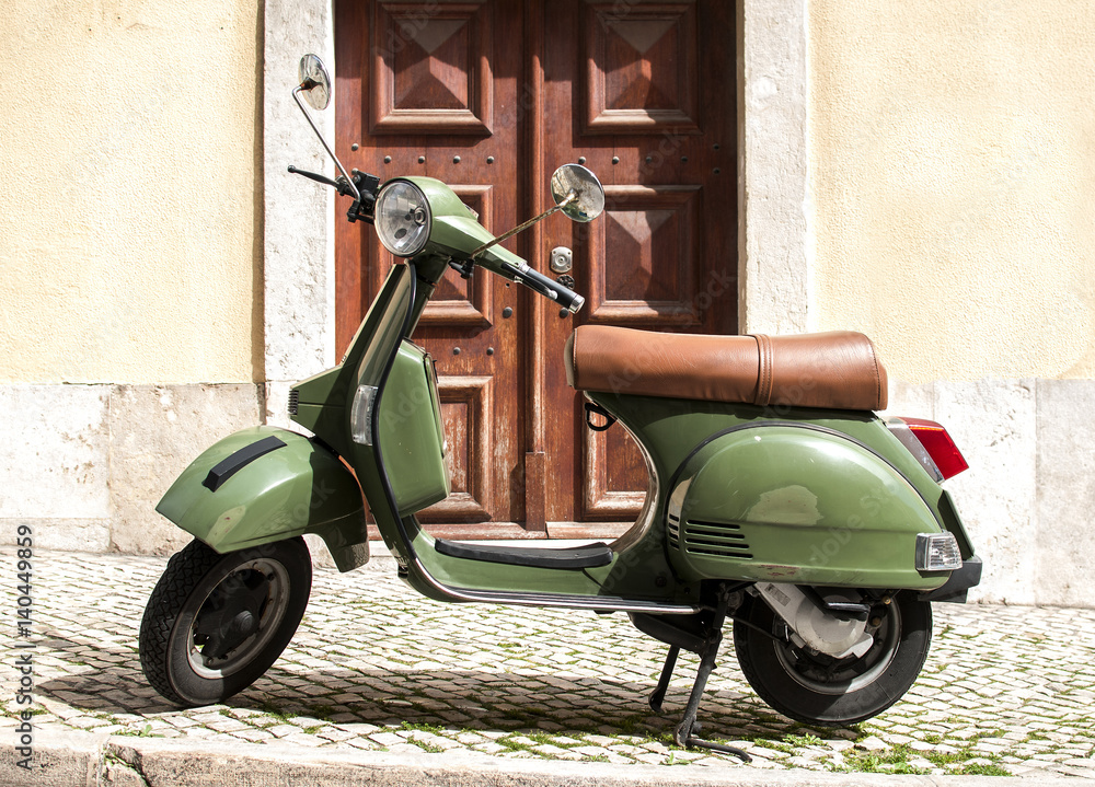 Green vintage motorcycle scooter staying on the cozy retro street in Lisbon, Portugal