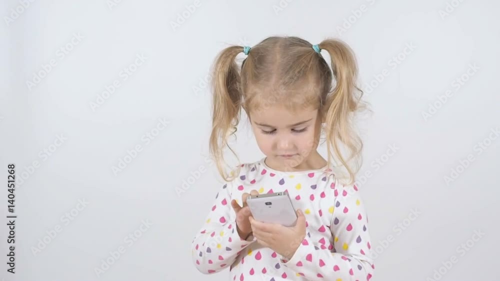 Little girl using smartphone isolated on a white background. Child playing with smartphone and wins. Little girl using smartphone isolated on a white background. Child playing with smartphone and wins.