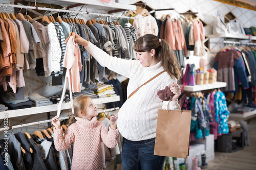 Woman and child choosing clothes for baby in store