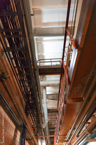 Ceiling in the shop of the production plant with iron pipes