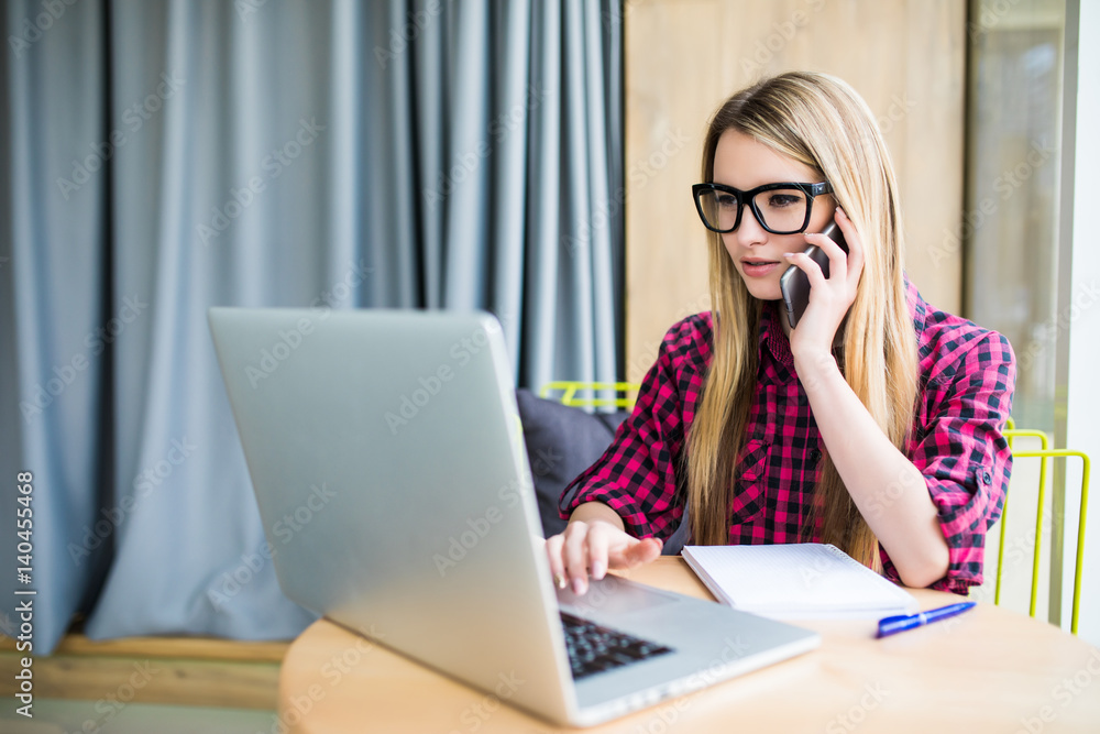 Young business woman, phoning at the office, worried expression on her face looking at laptop which is in front of her. Young business woman, phoning at the office, worried expression on her face looking at laptop which is in front of her.