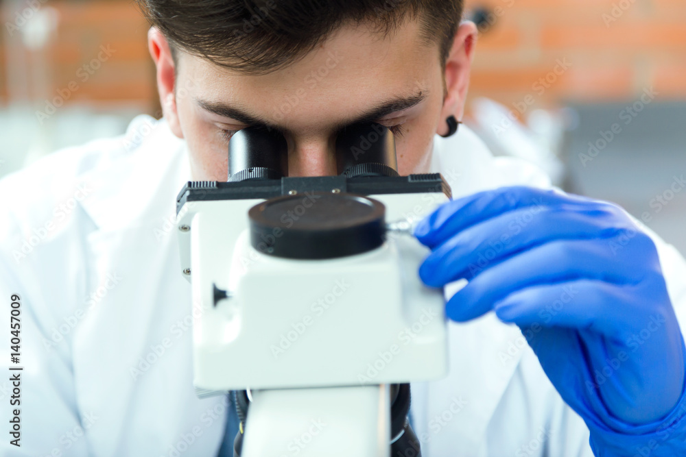 Young man looking through microscope in laboratory. Young man looking through microscope in laboratory.