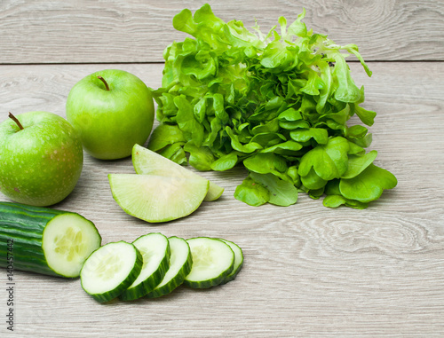 Green apples and vegetables on a wooden table, cooking. Dietary products. The concept of a healthy diet.