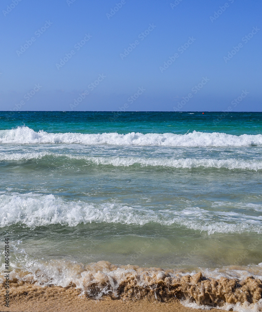 Waves run on a sandy beach, mixing with sand Waves run on a sandy beach, mixing with sand