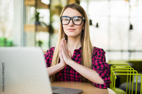 Young woman meditating sitting at the modern office desk in front of laptop, taking a pause, busy, stressful office, cure for work overload, one moment meditation, worshiping laptop photo