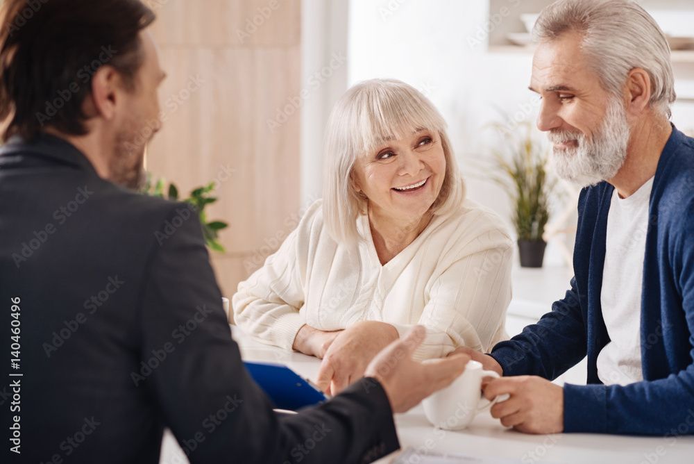 Cheerful elderly couple discussing contract at home Cheerful elderly couple discussing contract at home