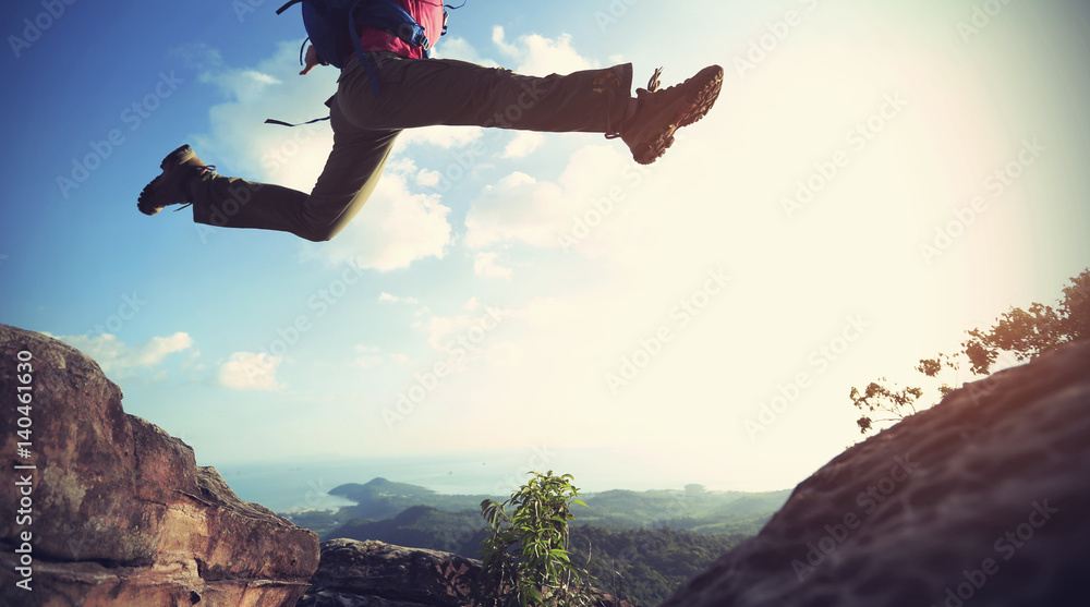 jumping over precipice between two rocky mountains . freedom, risk, challenge, success concept