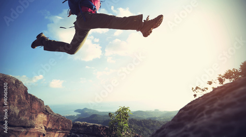 Photo jumping over precipice between two rocky mountains