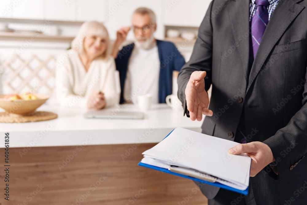 Obraz premium Credible social security advisor demonstrating document for elderly couple