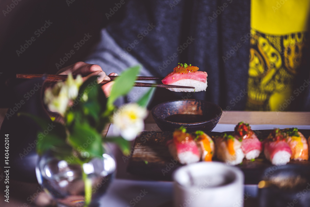 Man eating sushi set with chopsticks on restaurant Man eating sushi set with chopsticks on restaurant