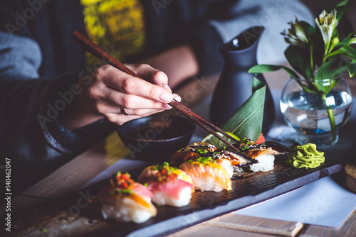 Fototapeta Man eating sushi set with chopsticks on restaurant