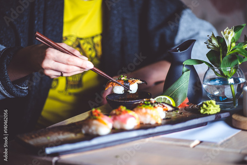 Man eating sushi set with chopsticks on restaurant