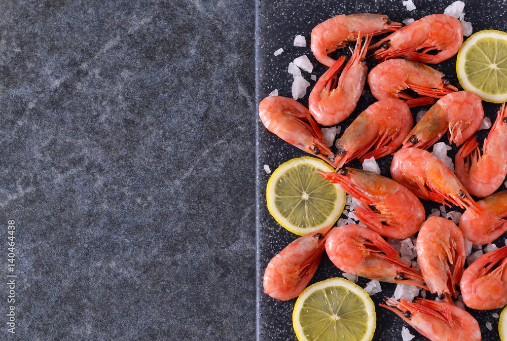 Boiled shrimps with salt and lemon on a marble, black background Boiled shrimps with salt and lemon on a marble, black background