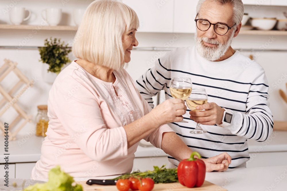 Positive couple of pensioners enjoying champagne in the kitchen Positive couple of pensioners enjoying champagne in the kitchen