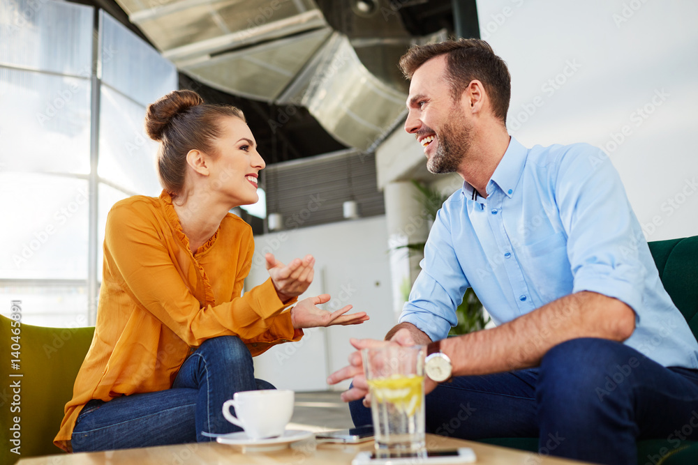 Happy couple discussing at cafe, office lobby during coffee break
