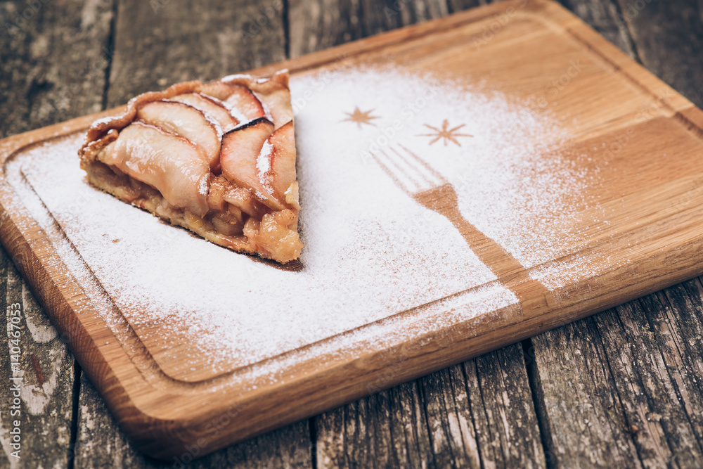 Fototapeta premium A piece of sliced apple pie with cinnamon on vintage wooden background texture.