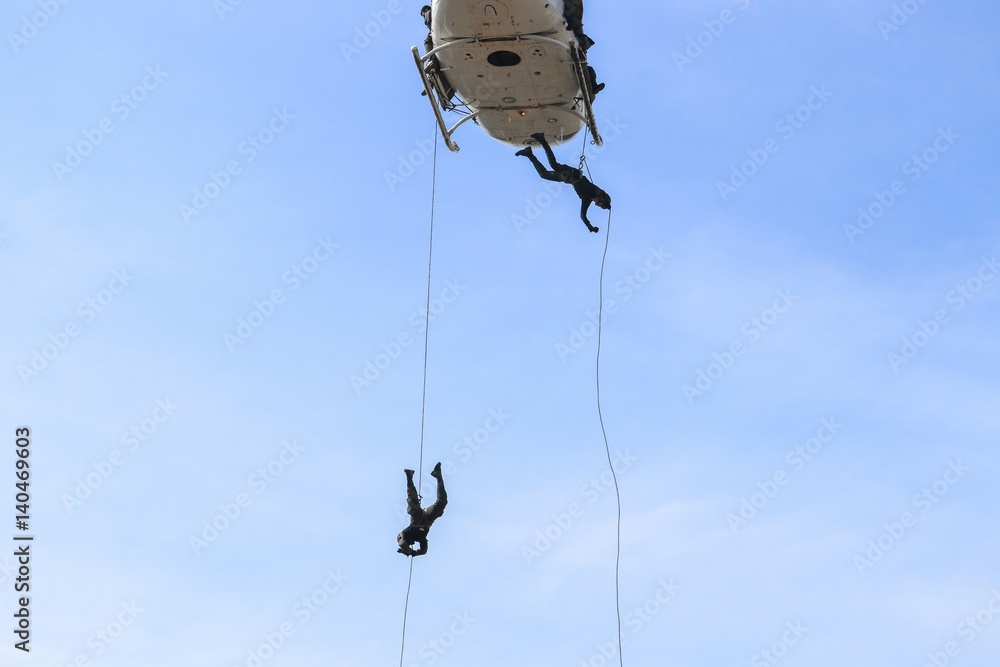 Soldier rappelling from helicopter in blue sky Soldier rappelling from helicopter in blue sky
