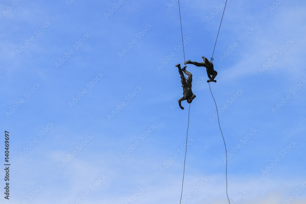 Soldier two rappelling with rope on blue sky Soldier two rappelling with rope on blue sky