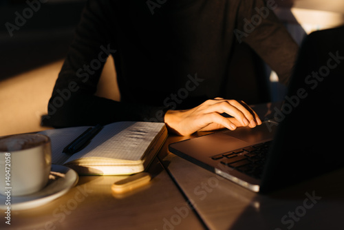 Woman's hands on keyboard and laptop in sunset light