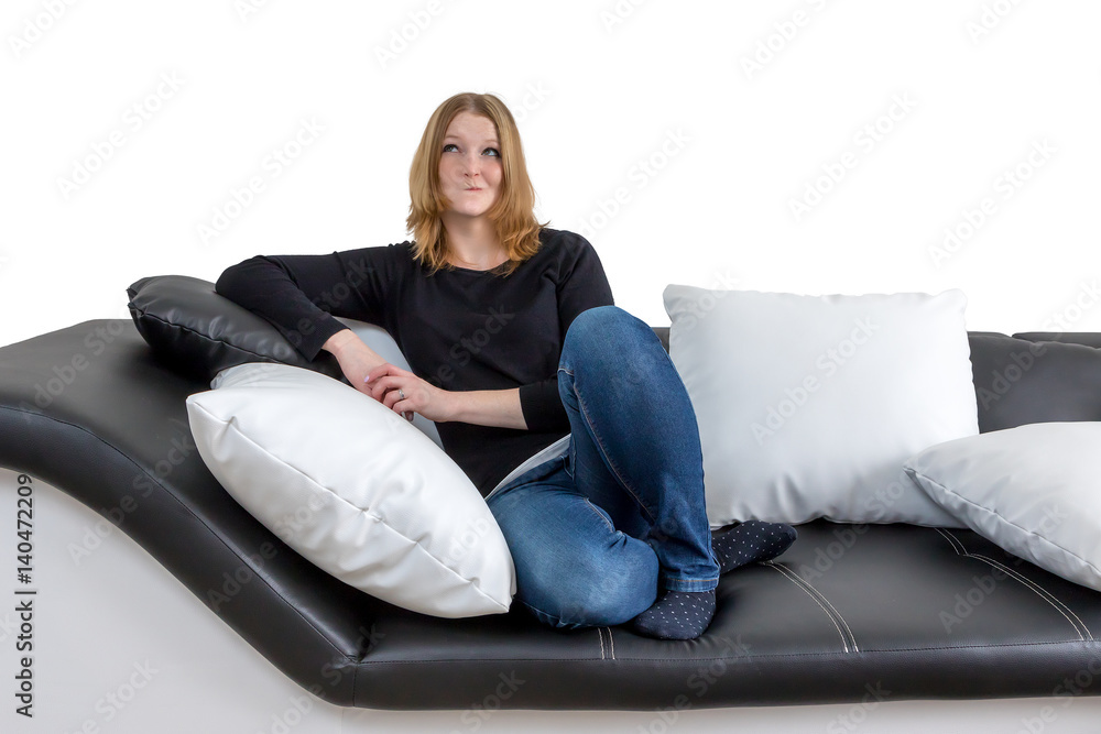 Grinning young woman is sitting on a black and white couch