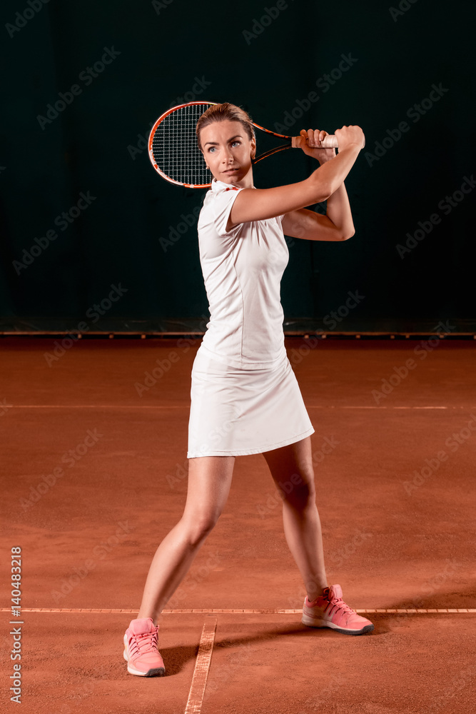 Sportswoman at the tennis court with racquet.
