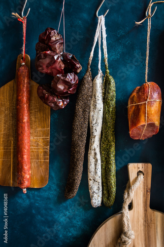 Assortment of sausages, Spanish charcuterie, wood cutting board, on dark blue background, gourmet, rustic photo