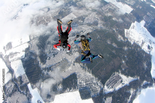 Two skydivers are training in the winter sky