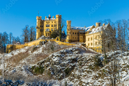 Hohenschwangau Castle in winter with blue sky and snow covered trees
