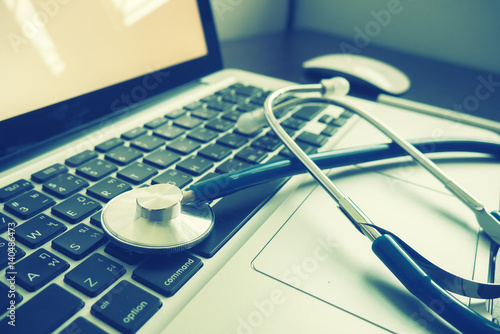Stethoscope,a medical instrument for listening to action of heart or breathing lay on laptop keyboard in doctor office,Medical concept ,relax time doctor,selective focus,vintage color.morning light