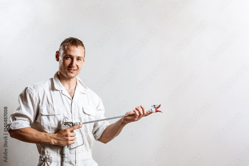 Worker holding spray gun over white wall. Copy space. Worker holding spray gun over white wall. Copy space.
