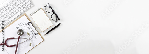 Top view of modern, sterile doctors office desk. Medical accessories on a white background with copy space around products.Workplace of a doctor. Stethoscope, clip board, glasses and other things