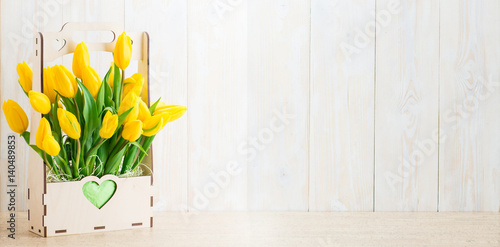 Fototapeta Naklejka Na Ścianę i Meble -  Yellow tulips in a wooden pot with copy space for text on a wooden background