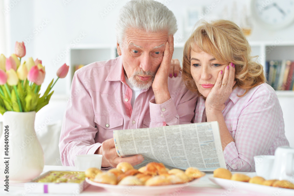 Elderly couple having breakfast and reading a newspaper