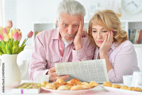 Elderly couple having breakfast and reading a newspaper