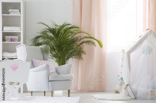 Baby room with armchair, crib and plant