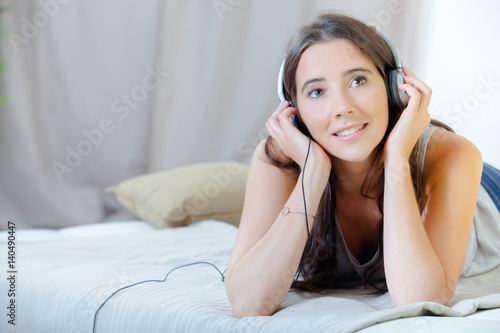 Lady listening to headphones, propped on elbows