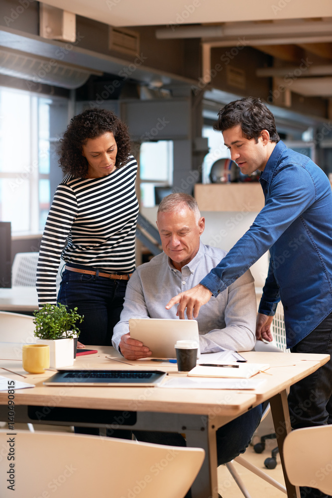 Business team talking together over a tablet in an office Business team talking together over a tablet in an office