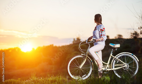 Woman with retro bike on the hill in the evening